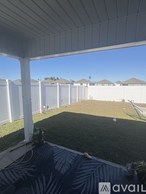 A patio with a white pillar and a white fence in the background.