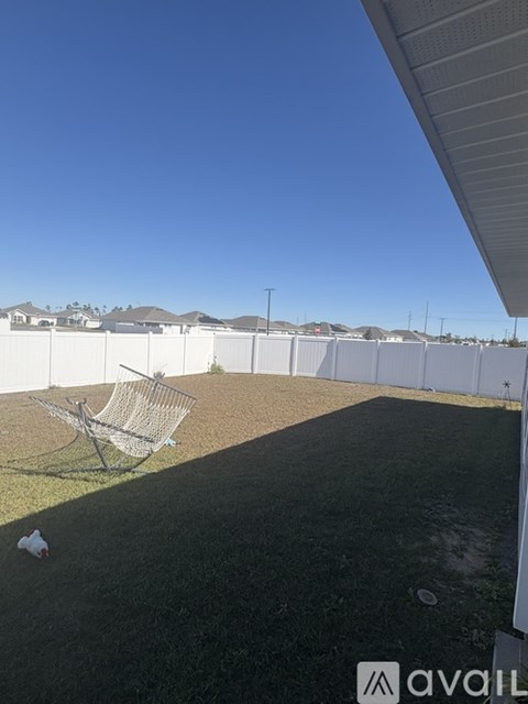 A metal chair is leaning against a fence in a grassy area.