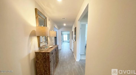 A hallway with a wooden cabinet and a mirror on the wall.