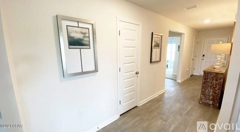 A hallway with a painting on the wall and a lamp on the side table.