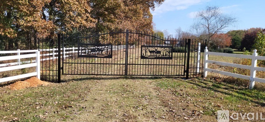 A black gate with a white fence in front of a field.