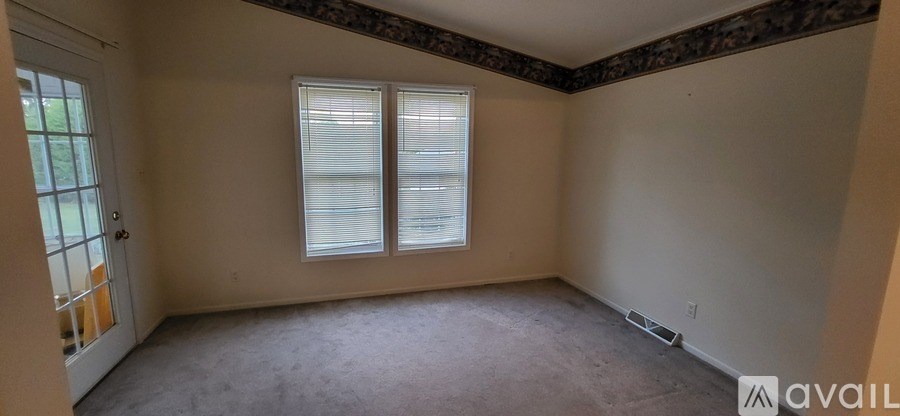 A room with a window and a door is available for rent.