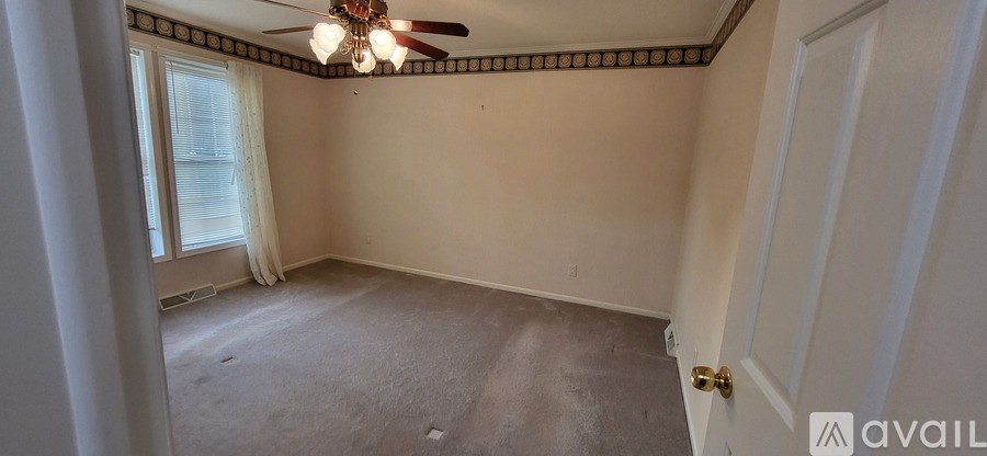 A room with a ceiling fan and a door.