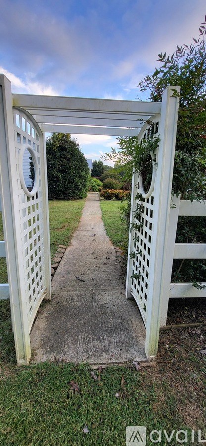A white gate with circular designs on the top is open.