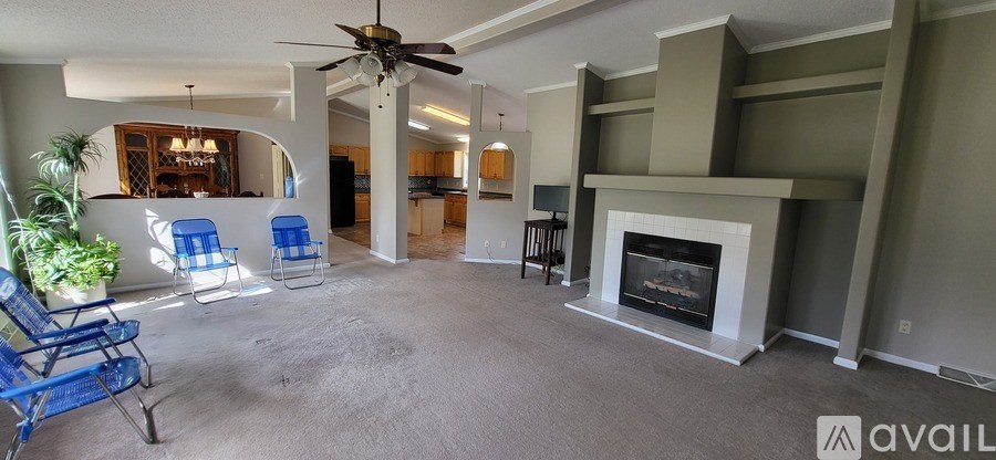 A living room with a fireplace and a ceiling fan.