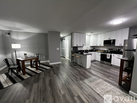 A well-lit kitchen and dining area with wooden flooring and white cabinetry.