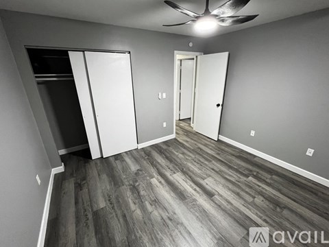 A room with a ceiling fan and a wooden floor.