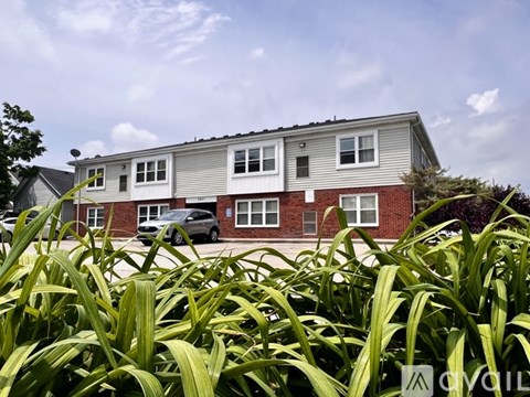 A grey and red house with a car parked in front.