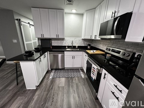 A modern kitchen with white cabinets and black countertops.