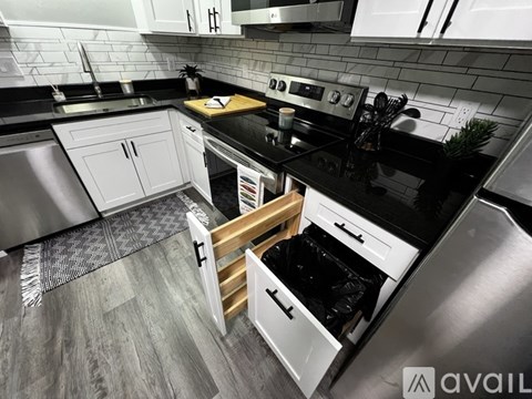 A modern kitchen with black countertops and white cabinets.