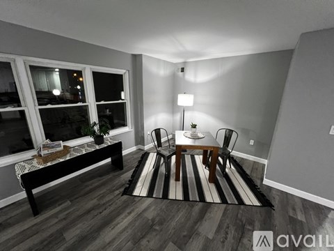 A living room with a black and white striped rug, a wooden coffee table, and two chairs.