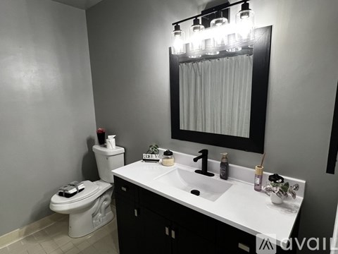 A bathroom with a toilet, sink, and mirror.
