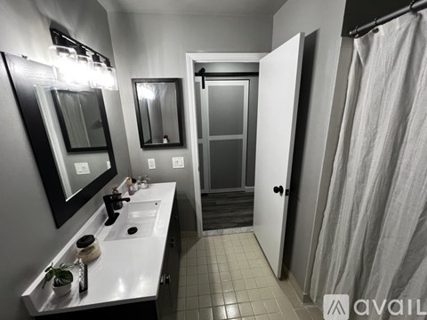 A bathroom with a sink, mirror, and shower.