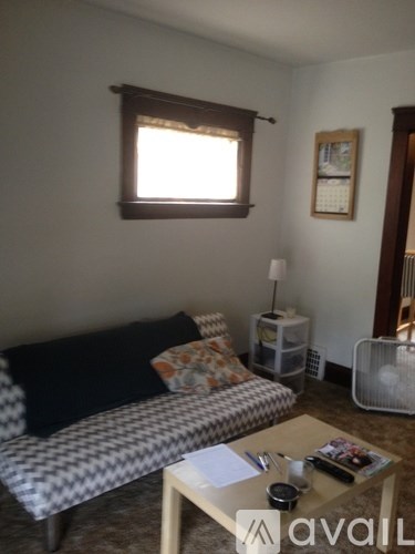 A living room with a couch, a table, and a window.