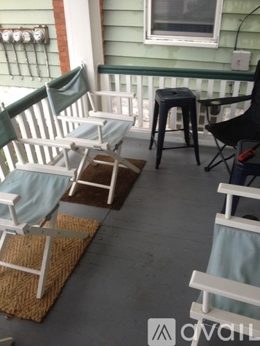A porch with two chairs and a stool.
