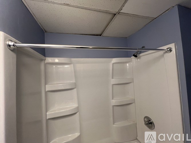 A white shower stall with a silver grab bar.
