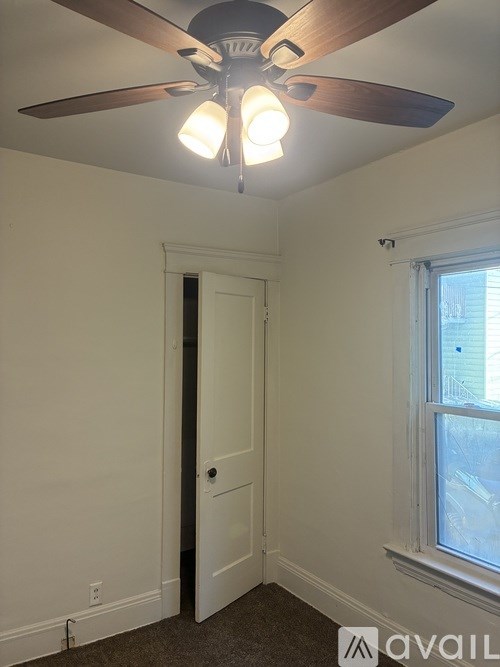 A room with a ceiling fan and a door.