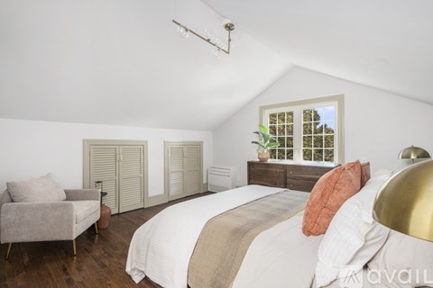 A bedroom with a bed, chair, and wardrobe.