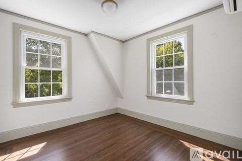 A room with two windows and wooden floors.