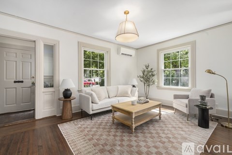 A living room with a white couch, a wooden coffee table, and a lamp.