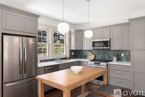 A kitchen with a wooden table and stainless steel appliances.