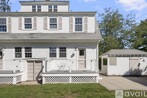 A white house with a porch and a gazebo-like structure to the right.