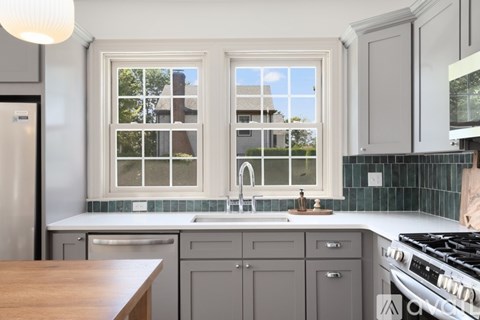A kitchen with a stove, sink, and window.