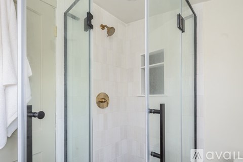 A glass shower door with a gold handle and a white towel hanging on the side.