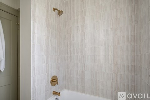 A bathroom with a shower and a white tiled wall.