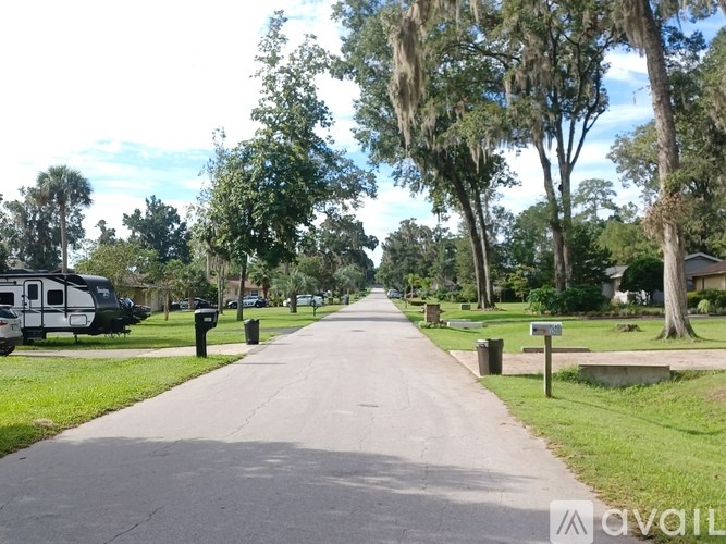 A tree-lined road with a parked RV on the left.