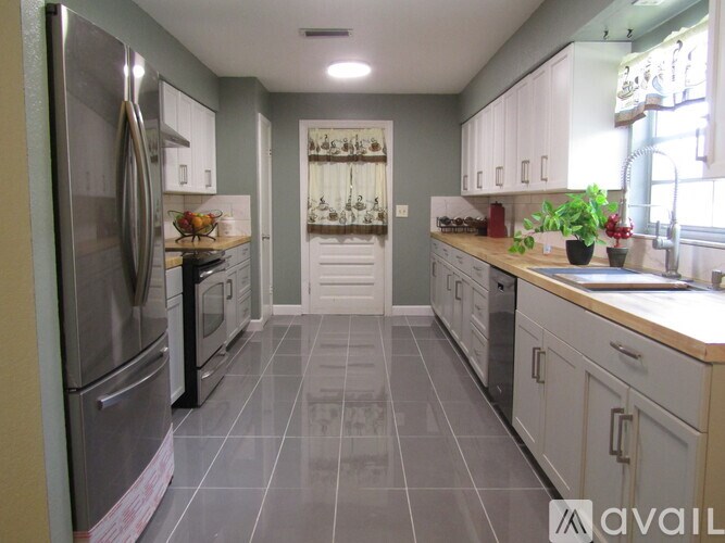 A kitchen with a refrigerator, oven, and sink.