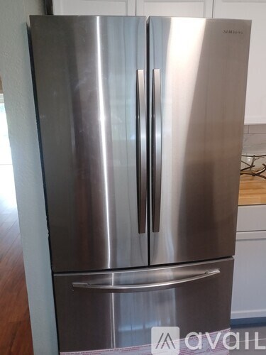 A silver fridge with the handle on the right side.