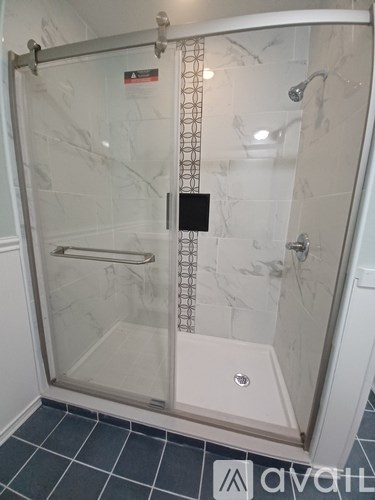A shower stall with a glass door and a white tile floor.