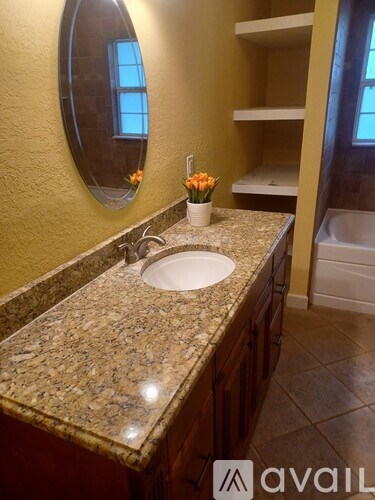A bathroom with a granite countertop and a round mirror.