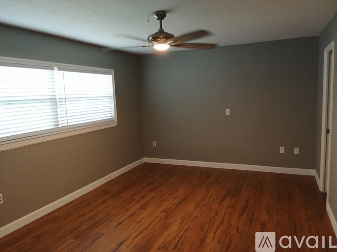 A room with a ceiling fan and wooden flooring.