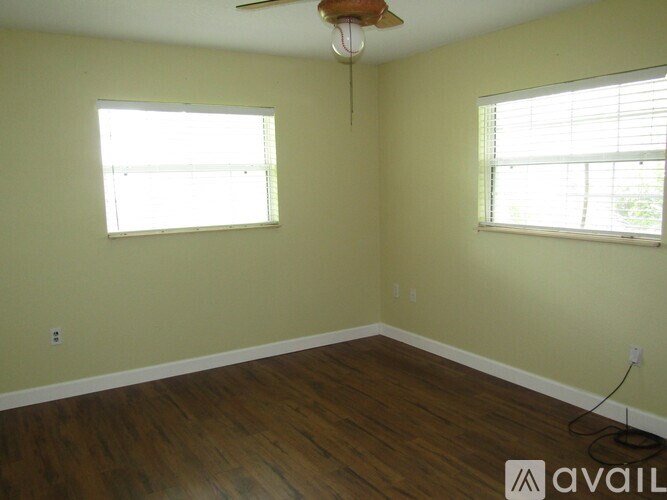 A room with a ceiling fan and two windows.