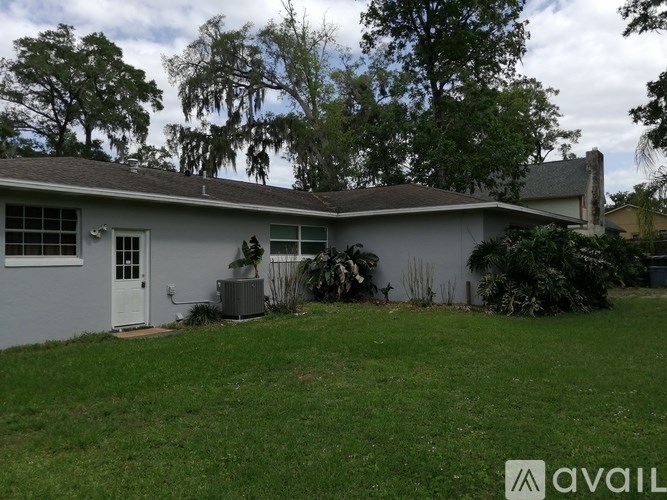 A house with a white door and a brown roof with a tree in the background.