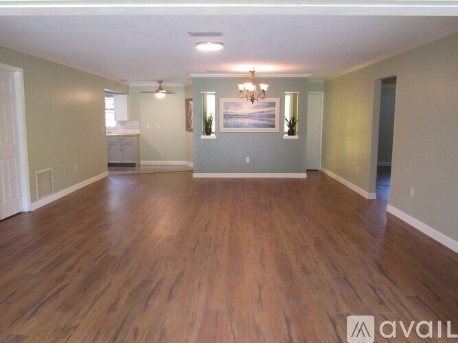 A spacious room with wooden floors and a chandelier.