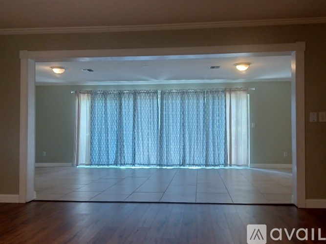 A room with a large window covered by a curtain.