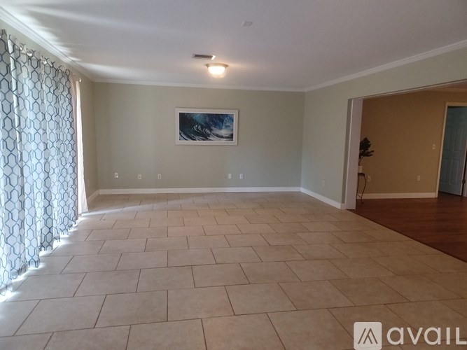 A spacious room with tiled flooring and a painting on the wall.