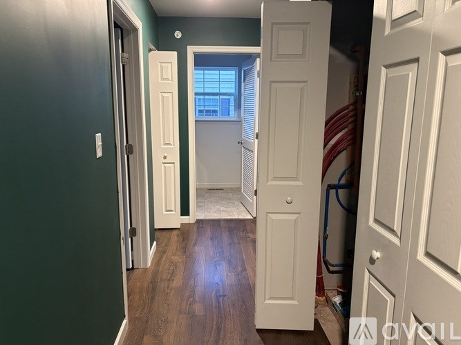 A hallway with white doors and a wooden floor.