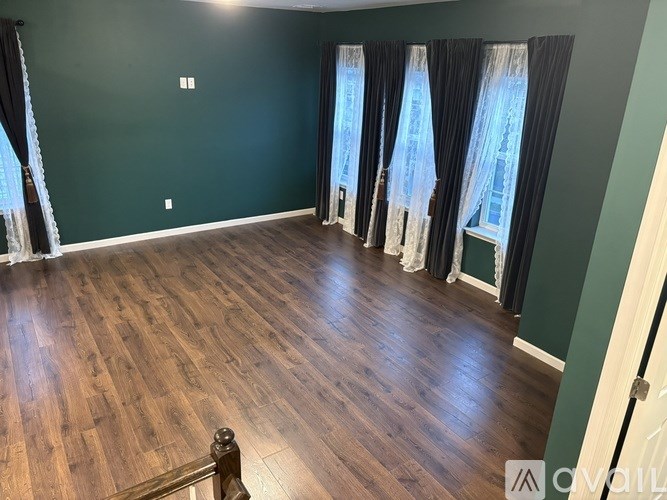 A room with wooden flooring and a window with curtains.