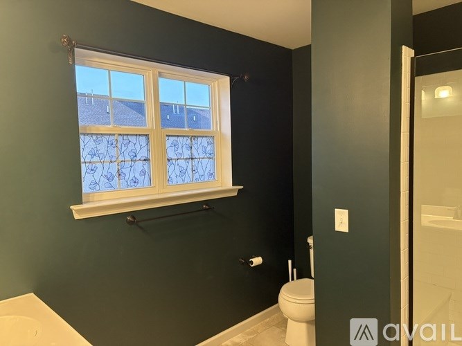 A bathroom with a toilet, sink, and window.