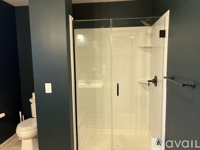 A bathroom with a toilet, a walk-in shower, and a towel bar.