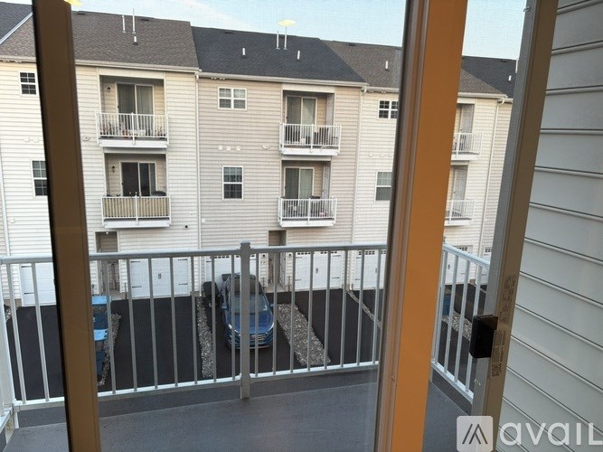A balcony with a table and chairs and a car parked in the background.