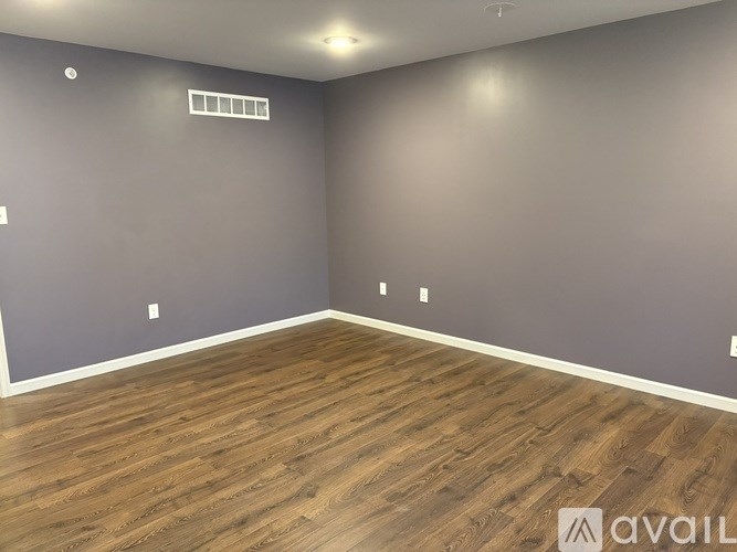 A room with wooden flooring and grey walls.
