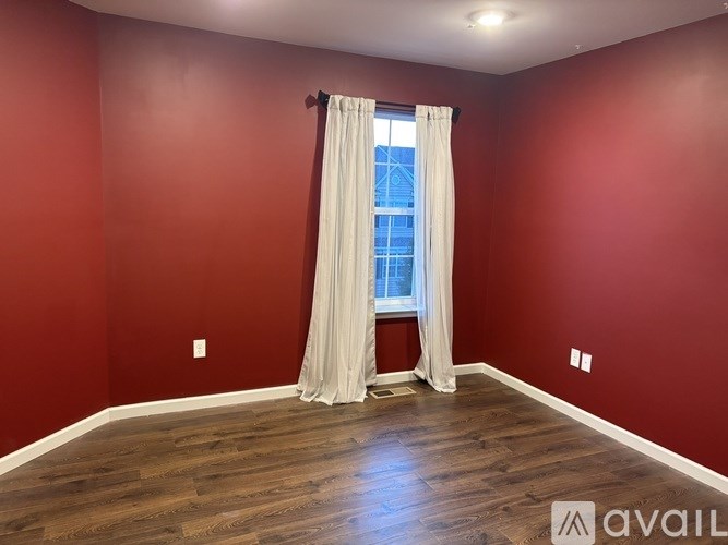 A room with red walls and a window with white curtains.
