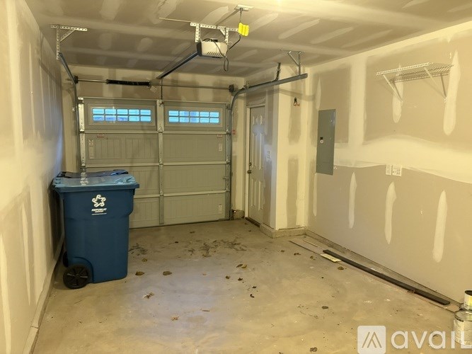 A room with a blue trash bin and white walls.