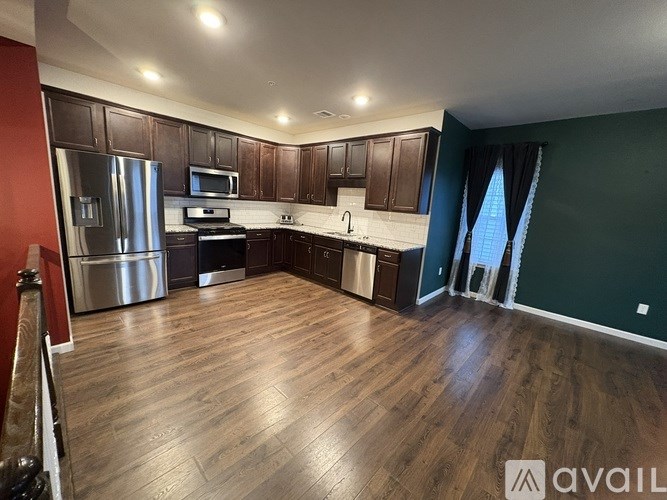 A kitchen with dark wood cabinets and a stainless steel refrigerator.
