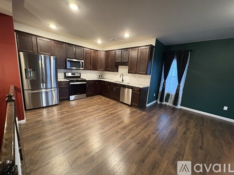A kitchen with dark wood cabinets and a stainless steel refrigerator.